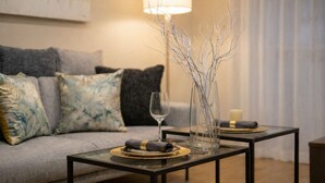 A modern living room with a sofa, a glass coffee table, a lamp, and a vase with branches. - KISEN KOBE EKIMAE (Kobe)