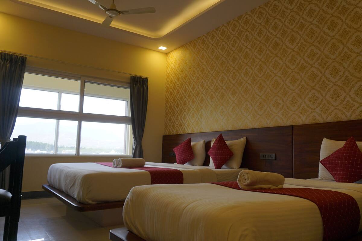 A hotel room with two beds, a large window, and a patterned wall.
