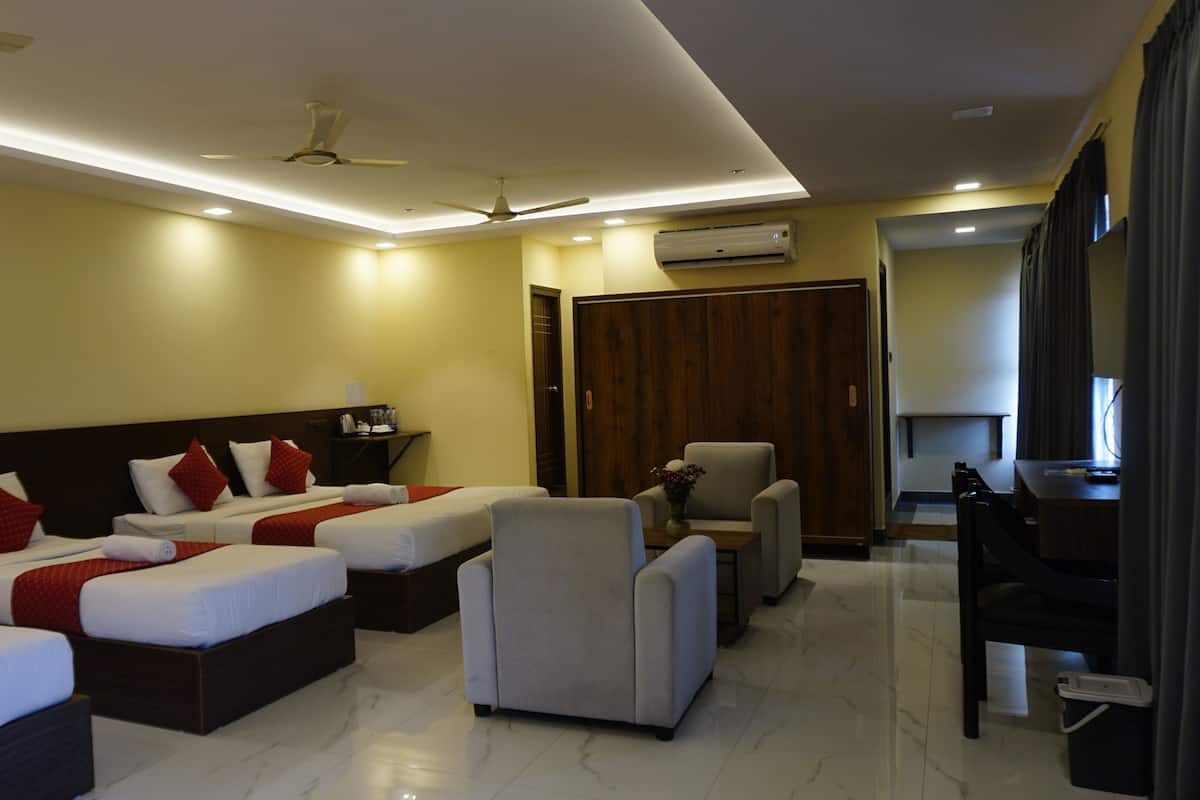 A hotel room with two beds, a desk, a chair, a wardrobe, and a ceiling fan.