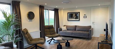 A modern living room with a sofa, armchair, coffee table, and a television.