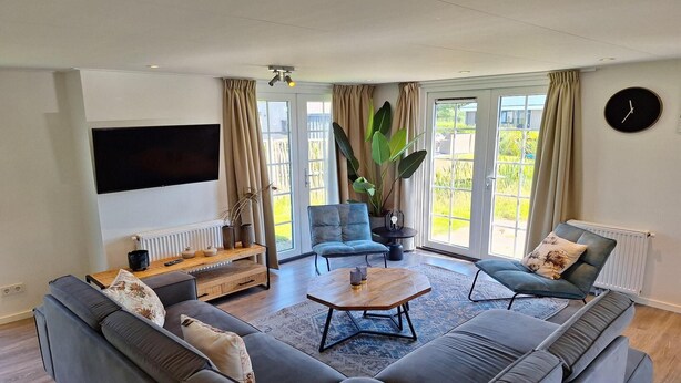 A modern living room with a large sofa, a coffee table, a TV, and a large plant.