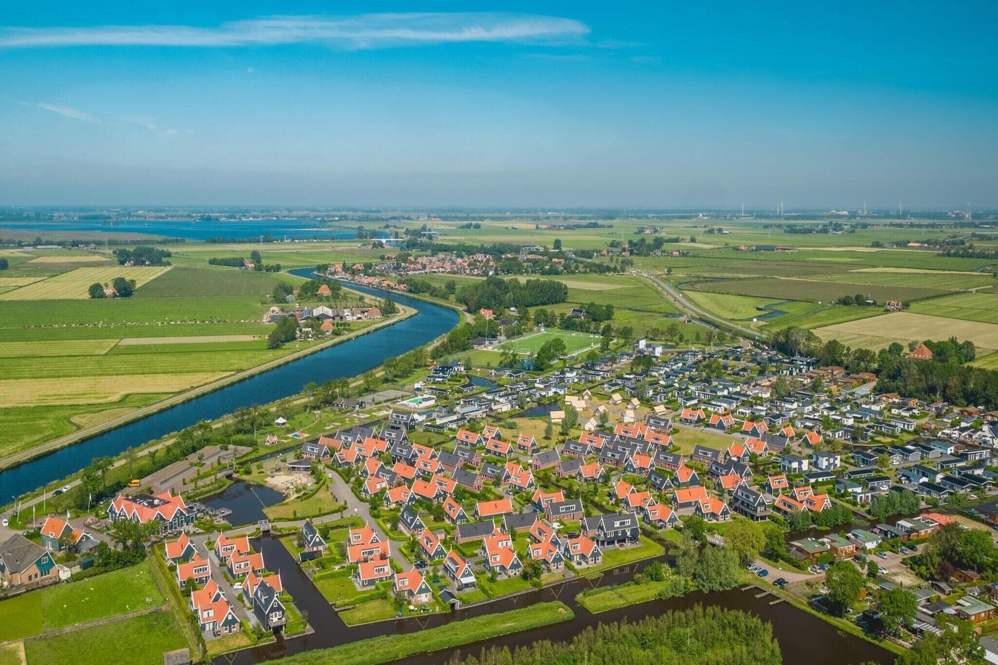 Luchtbeeld van een woongebied met huizen, een rivier en velden.