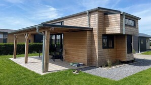 Ein modernes, zweistöckiges Haus mit überdachter Terrasse, Garage und gepflegtem Rasen.