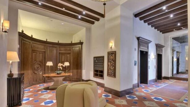 A lobby with a patterned floor, a reception desk, and a large wooden door. - Luxury 2-bedroom townhome with AC in San Jose (San Jose)