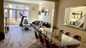 A spacious living area with a glass dining table, leather sofa, and a large mirror. - Luxury 2-bedroom townhome with AC in San Jose (San Jose)