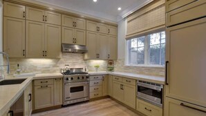 A kitchen with beige cabinets, a stainless steel range hood, a double oven, and a window with blinds. - Luxury 2-bedroom townhome with AC in San Jose (San Jose)