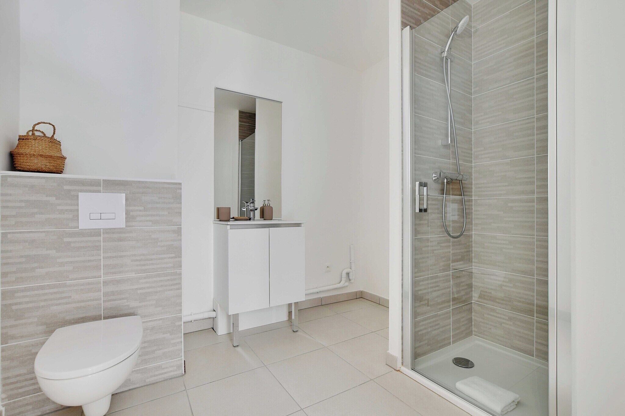 Une salle de bain moderne équipée de toilettes, d’un lavabo, d’un miroir et d’une douche.