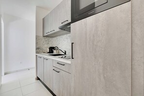 A modern kitchen with a marble backsplash, stainless steel appliances, and light-colored cabinetry. - Elegant Appt - 1BDR/2P - Near Paris & La Défense (Suresnes)