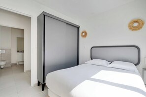A modern bedroom with a bed, a wardrobe, and a bathroom visible through an open door. - Elegant Appt - 1BDR/2P - Near Paris & La Défense (Suresnes)