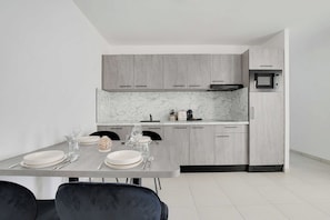 A modern kitchen with grey cabinets, a marble countertop, and a built-in microwave. - Elegant Appt - 1BDR/2P - Near Paris & La Défense (Suresnes)