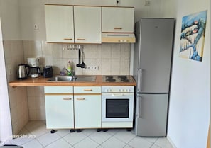 A compact kitchen with a refrigerator, stove, oven, and a sink.