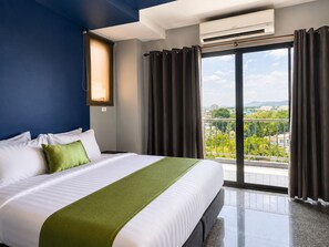 A hotel room with a large bed, a view of the city, and an air conditioning unit. - iCheck inn Phuket Town (Phuket)