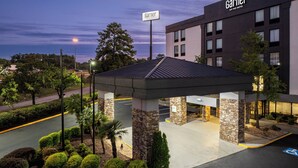 A hotel entrance with a covered waiting area, a sign for the hotel, and a parking lot with a handicapped parking space. - Augusta West (Augusta)