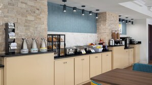 A modern kitchen with a stone wall, a black countertop, and a wooden dining table. - Augusta West (Augusta)