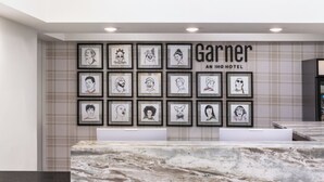 A hotel reception area with a marble counter, framed portraits on the wall, and a sign reading 'Garnier AN IHG HOTEL'. - Augusta West (Augusta)