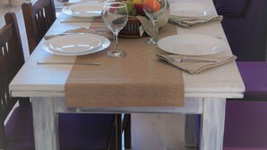 Una mesa de comedor con platos, vasos y una cesta de frutas.