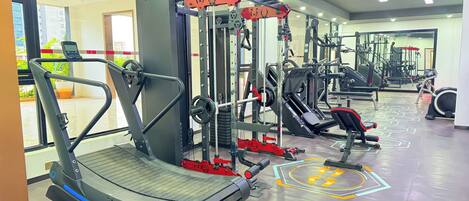 Une salle de sport équipée de tapis de course, d’appareils de musculation et d’un mur recouvert de miroirs.