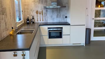 Een moderne keuken met een inbouwoven, roestvrijstalen apparatuur en een raam.