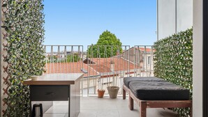 En balkon med seng, et lille bord og plantekasser.