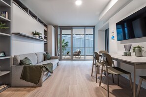 Ein modernes Wohnzimmer mit Sofa, Esstisch, Stühlen und Fernseher.