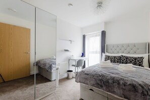 A bedroom with a bed, a desk, a chair, a wardrobe, and a mirror. - Beautifully Presented 2BDR Flat in Canada Water (Greater London)