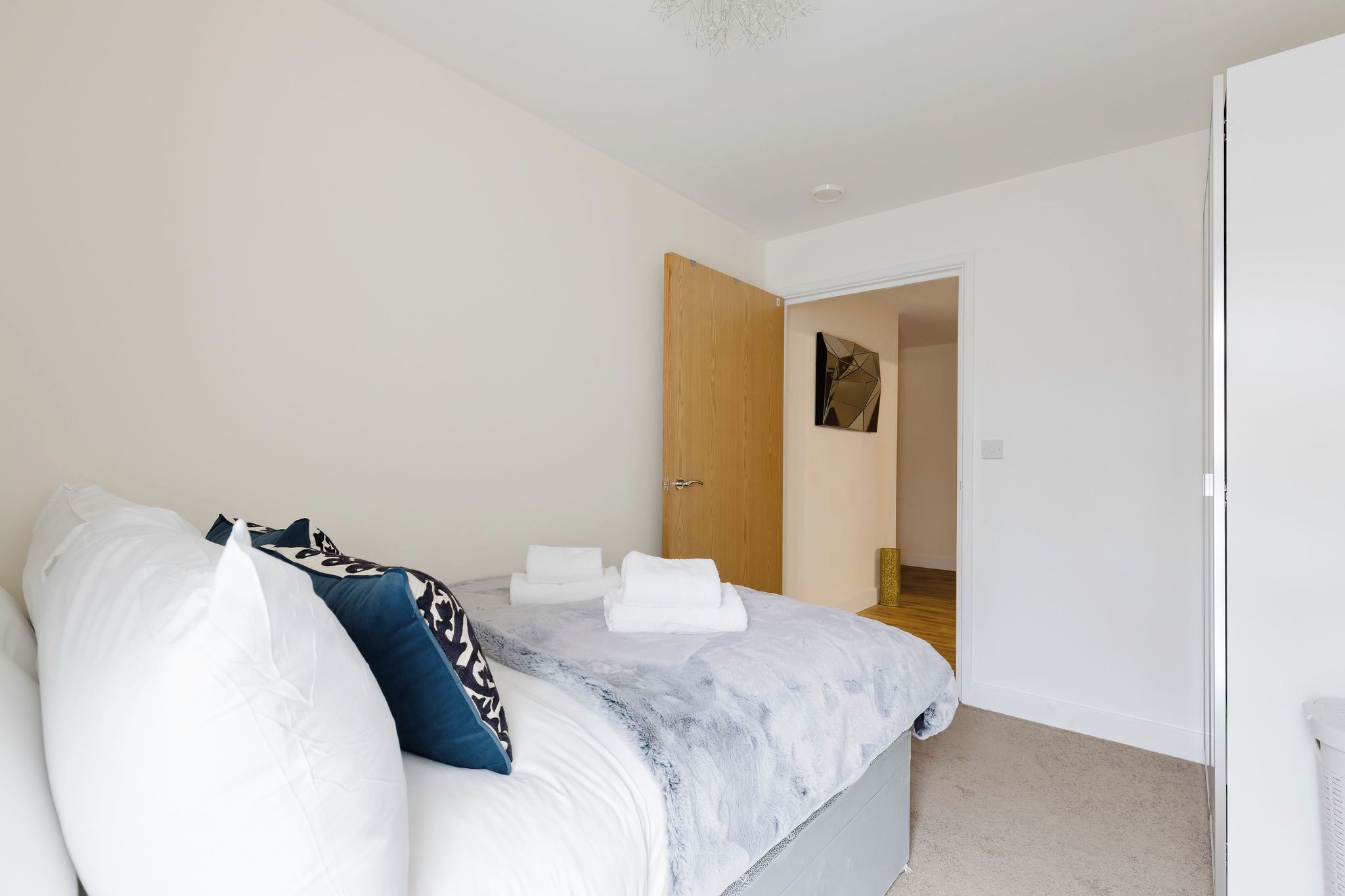 Un dormitorio con cama, almohadas y una puerta que da a otra habitación.