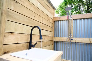 A wooden exterior wall with a white sink and a shower area. - Boutique Surf Studio by the Beach (Newquay)