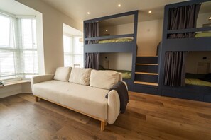A room with a sofa, bunk beds, and a window with blinds. - Boutique Surf Studio by the Beach (Newquay)
