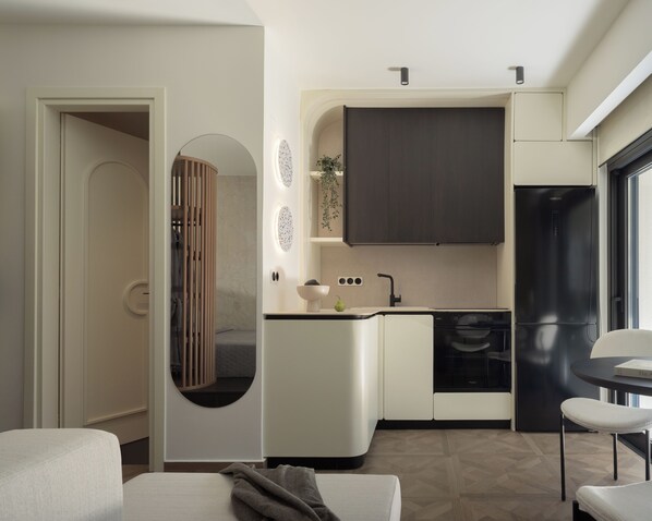 Cocina compacta con horno integrado, lavamanos y refrigerador.  Cuenta con una zona de comedor con mesa y sillas.
