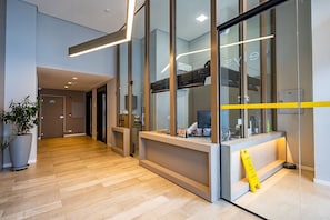 Un espace d’accueil moderne comprenant un comptoir de réception, une plante en pot et un panneau d’avertissement jaune.