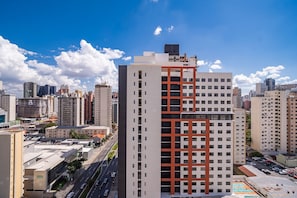Un immeuble de grande hauteur au design moderne, caractérisé par une façade rouge et blanche bien visible, entouré d’autres bâtiments et se dressant sous un ciel dégagé.