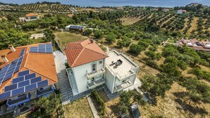 A residential area with houses, solar panels, and a view of the sea. - Sunrise Villa No 1 - Agios Nikolaos Halkidiki (Vourvourou)