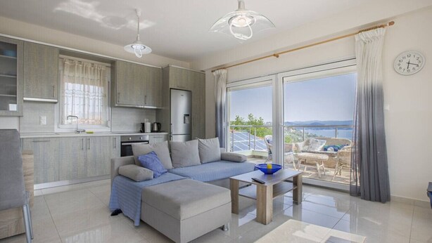 A modern living room with a sofa, a coffee table, and a view of the sea. - Sunrise Villa No 1 - Agios Nikolaos Halkidiki (Vourvourou)