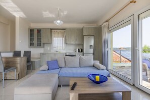 Ein modernes Wohnzimmer mit Sofa, Couchtisch und Blick auf die Küche und den Balkon.