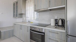 A modern kitchen with grey cabinetry, a stainless steel refrigerator, a built-in oven, and a coffee maker. - Sunrise Villa No 1 - Agios Nikolaos Halkidiki (Vourvourou)