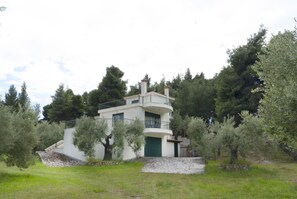 A two-story building with a curved balcony, surrounded by olive trees. - Nature Green House by RentalsPro - Akti Elia Halkidiki (Nikiti)