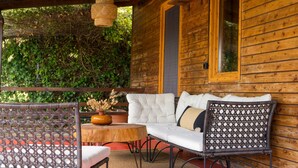 A wooden cabin with a balcony, wicker furniture, and a vase with dried flowers. - Casa Mocha by RentalsPro - Vourvourou Halkidiki (Vourvourou)