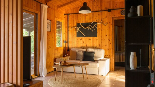 A wooden interior with a sofa, a table, and a hanging light fixture. - Casa Mocha by RentalsPro - Vourvourou Halkidiki (Vourvourou)
