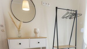 A white console table with a mirror, two baskets, and a woven floor mat.