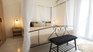 A bedroom with a four-poster bed, bedside tables, a bench, and a large window with curtains.