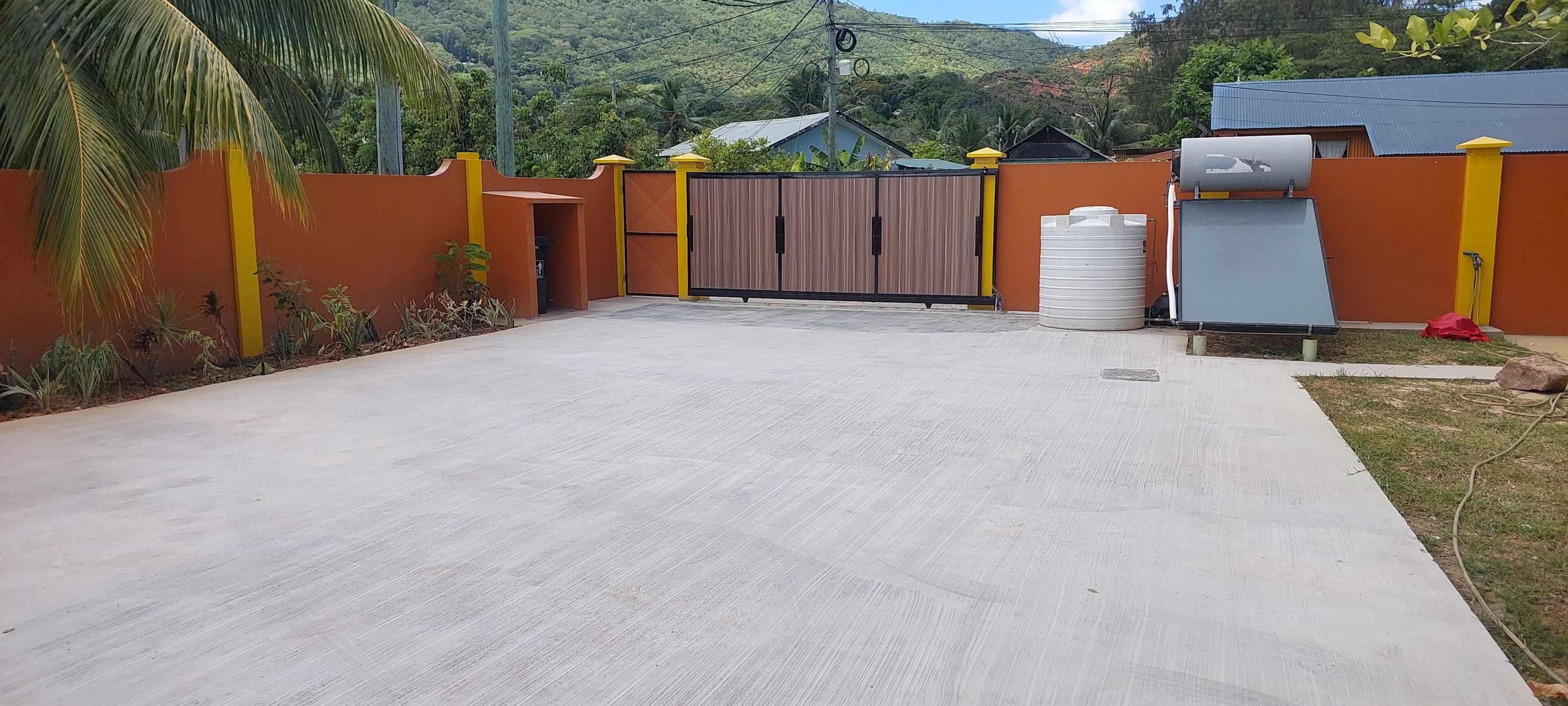 A paved courtyard with a gated entrance, a water tank, and a solar panel.