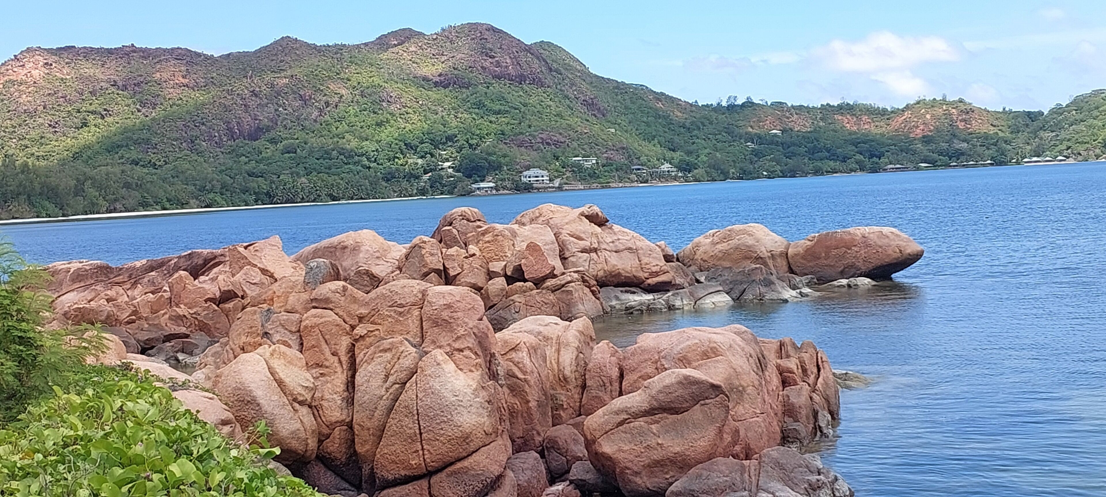 Une côte rocheuse bordant un lac paisible, avec des collines en arrière-plan.
