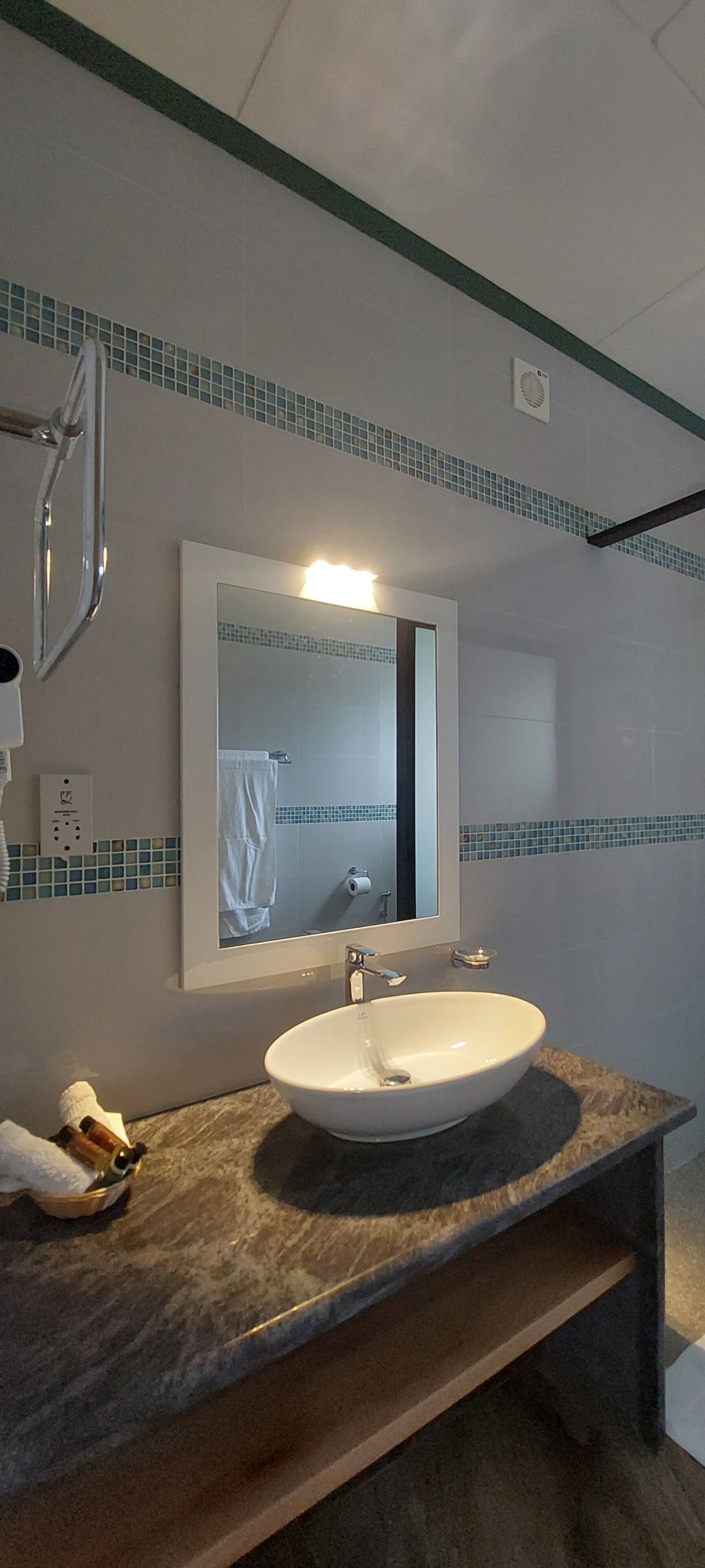 Un bagno con un lavabo in marmo, uno specchio e un portasciugamani.