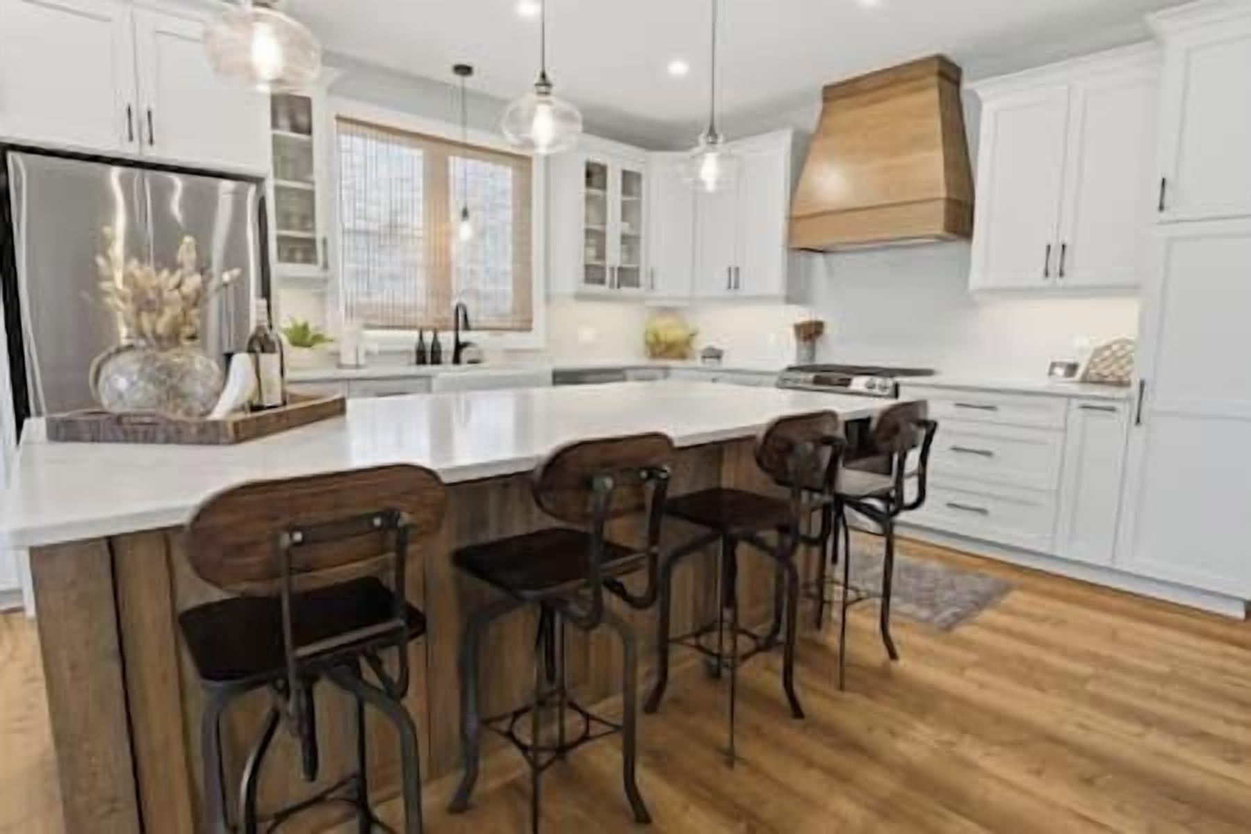 A modern kitchen with white cabinetry, a large island with bar stools, and pendant lighting.