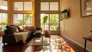 A modern living room with a sofa, coffee table, and large windows. - Urban Loft Perch • City Views • Free Parking (Vancouver)