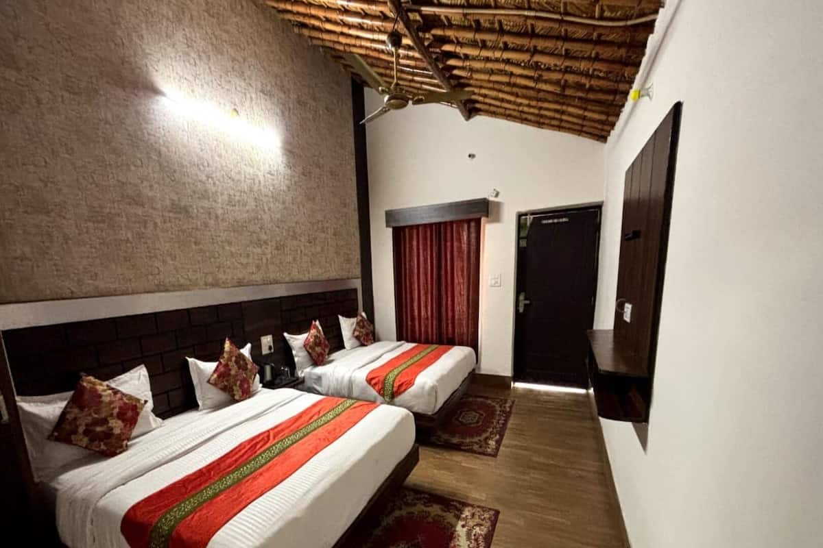 A hotel room with two beds, a wooden ceiling, a red curtain, and a wooden floor.