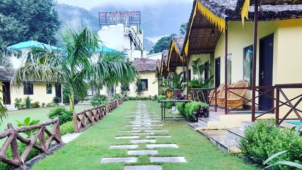 A pathway leading to a row of thatched-roof buildings with a sign reading 'VIAHAYA HOTEL'. - Nakshatra Resort (Rishikesh)
