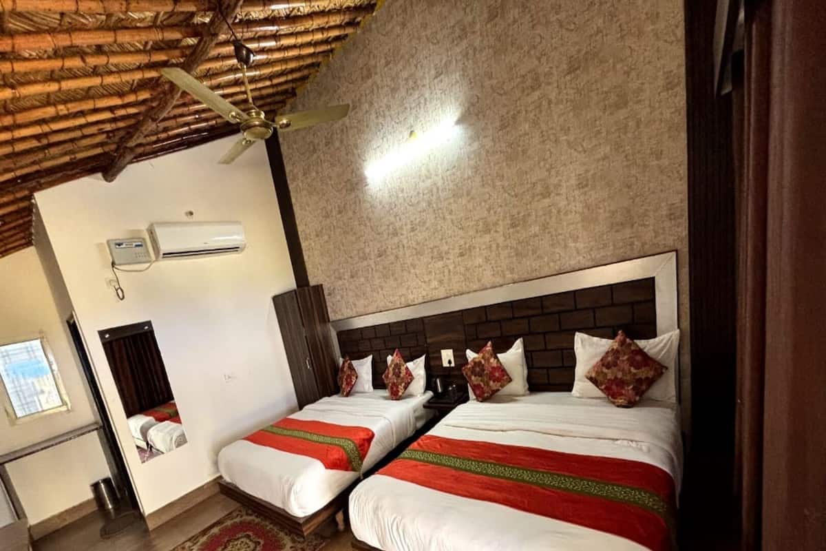 A hotel room with two beds, a wooden ceiling, a wall-mounted air conditioner, and a patterned rug.