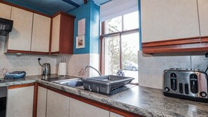A kitchen with a granite countertop, stainless steel sink, and a toaster. - Islay Cottage (Kingussie)