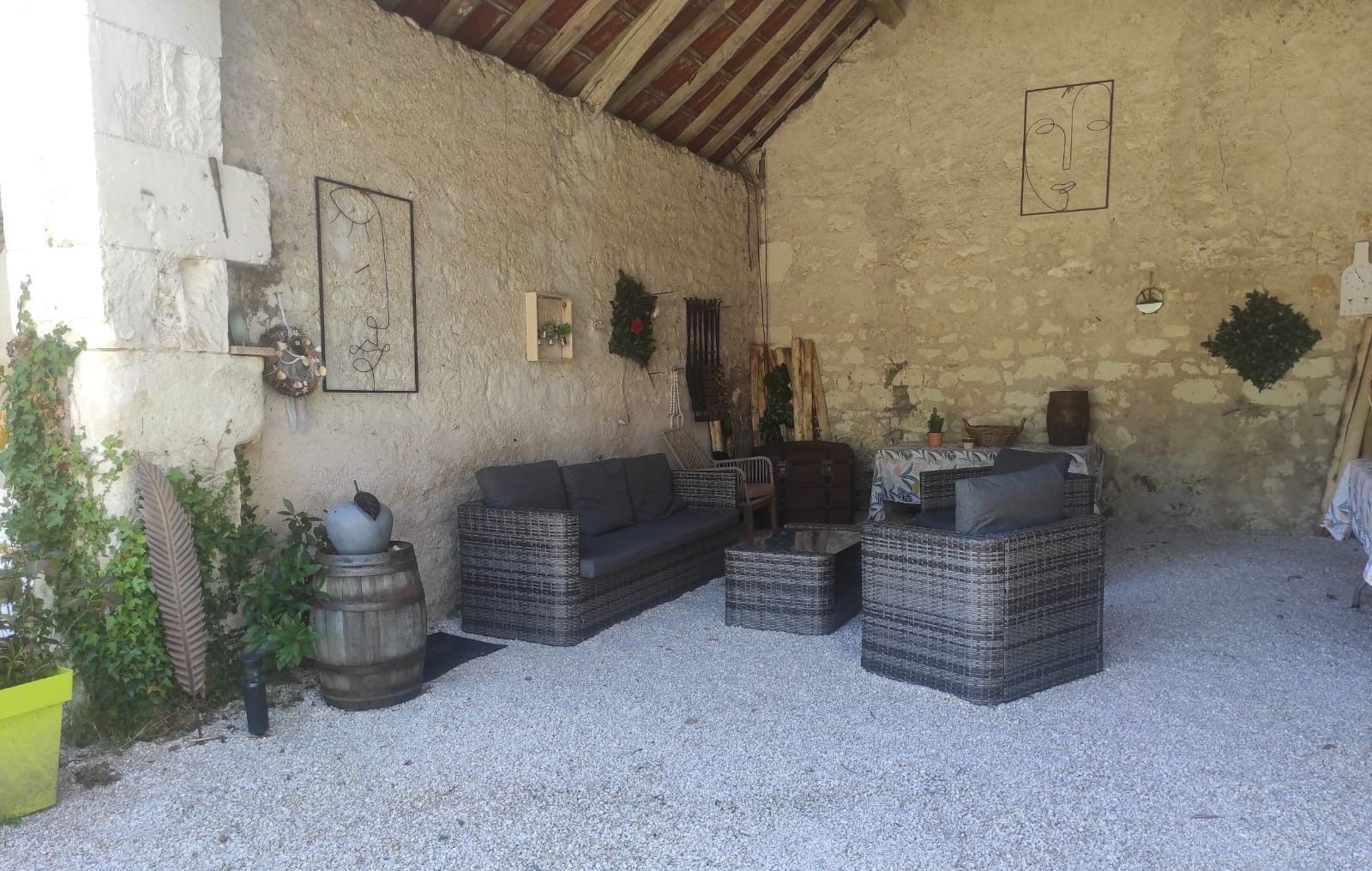 Un intérieur rustique avec des meubles en osier, un mur en pierre et un plafond avec des poutres en bois.